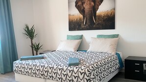 A modern bedroom with a large bed, a wall-mounted elephant picture, and a small plant.