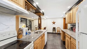 Una cocina con armarios de madera, encimera de granito, estufa blanca y un adorno con forma de estrella en la pared.