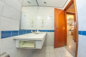 Ein Badezimmer mit einem weißen Waschbecken, zwei weißen Telefonen an der Wand und einer Holztür zu einem anderen Raum.