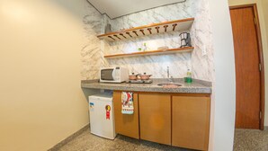 Una cocina compacta equipada con microondas, cafetera y refrigerador pequeño.