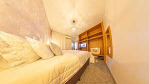 Una habitación de hotel con una cama grande, un armario de madera, un televisor y piso alfombrado.