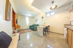 Ein kleiner Wohnbereich mit Essplatz, Küche und einem grünen Sofa.