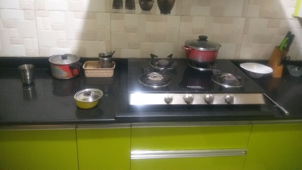 Una cocina con estufa a gas, ollas, tetera y un lavabo.