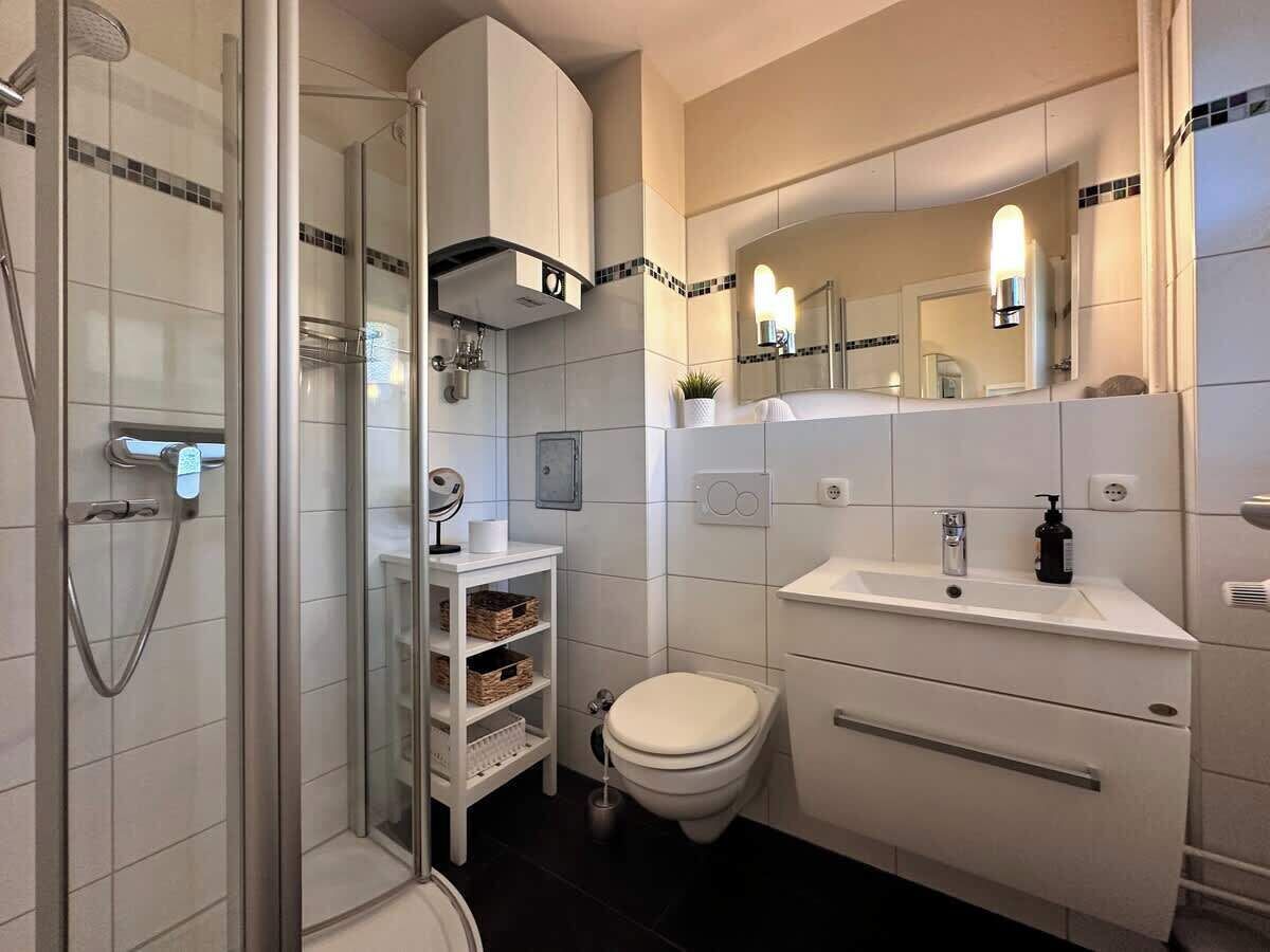 A modern bathroom with a glass shower enclosure, a toilet, a sink, and a vanity with a mirror.