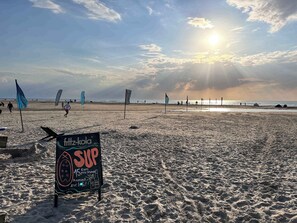 Une plage avec un panneau publicitaire indiquant qu’une boisson est proposée à 15 euros et une collation à 21 euros.