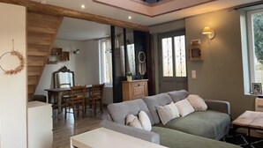 A spacious living area with a high ceiling, a dining area, and a staircase leading to an upper level. - Juliette's garden (Gournay-le-Guérin)
