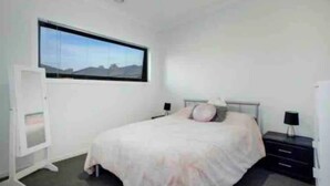 A bedroom with a bed, a window, a wardrobe, and a nightstand. - ADORABLE 2 Bedroom + Study Villa - free parking. (Rosebud)