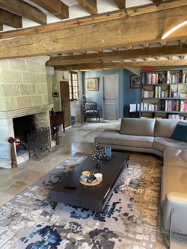 Un salón amplio con chimenea, un sofá, una mesa de centro y una estantería.