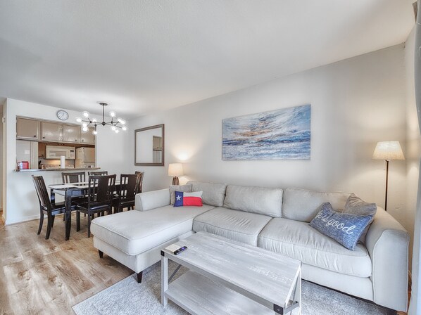 Ein Wohnzimmer mit Sofa, Couchtisch und einem Essbereich mit Stühlen und Tisch.