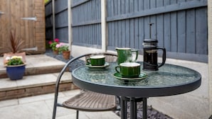 A round metal table with a green coffee pot, a green cup, and a black coffee maker. - Cheerful and modern one bedroom home with parking - Pass the Keys (Shrewsbury)
