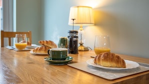 A breakfast table with croissants, a coffee pot, and glasses of orange juice. - Cheerful and modern one bedroom home with parking - Pass the Keys (Shrewsbury)
