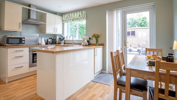 A modern kitchen with white cabinetry, a built-in microwave, and a large island with a sink. - Cheerful and modern one bedroom home with parking - Pass the Keys (Shrewsbury)