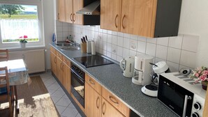 A modern kitchen with wooden cabinets, a granite countertop, a built-in oven, and a coffee maker. - Vacation at the Baltic Sea - beautiful vacation apartment for 4 persons (Warnow)