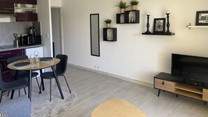 A modern living room with a dining area, a kitchen, and a TV. - Grand Studio à la Coudouliere Proche de la Plage (Six-Fours-les-Plages)