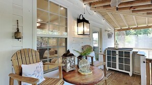 A wooden deck with a round table, two wooden chairs, a lantern, and a cabinet. - The Fort | Private Pool, Fire Pit Arcade Games (Tybee Island)