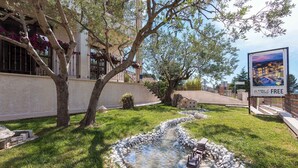 A courtyard with a small pond, trees, and a building with a balcony. - Holiday apartment with terrace (Fažana)