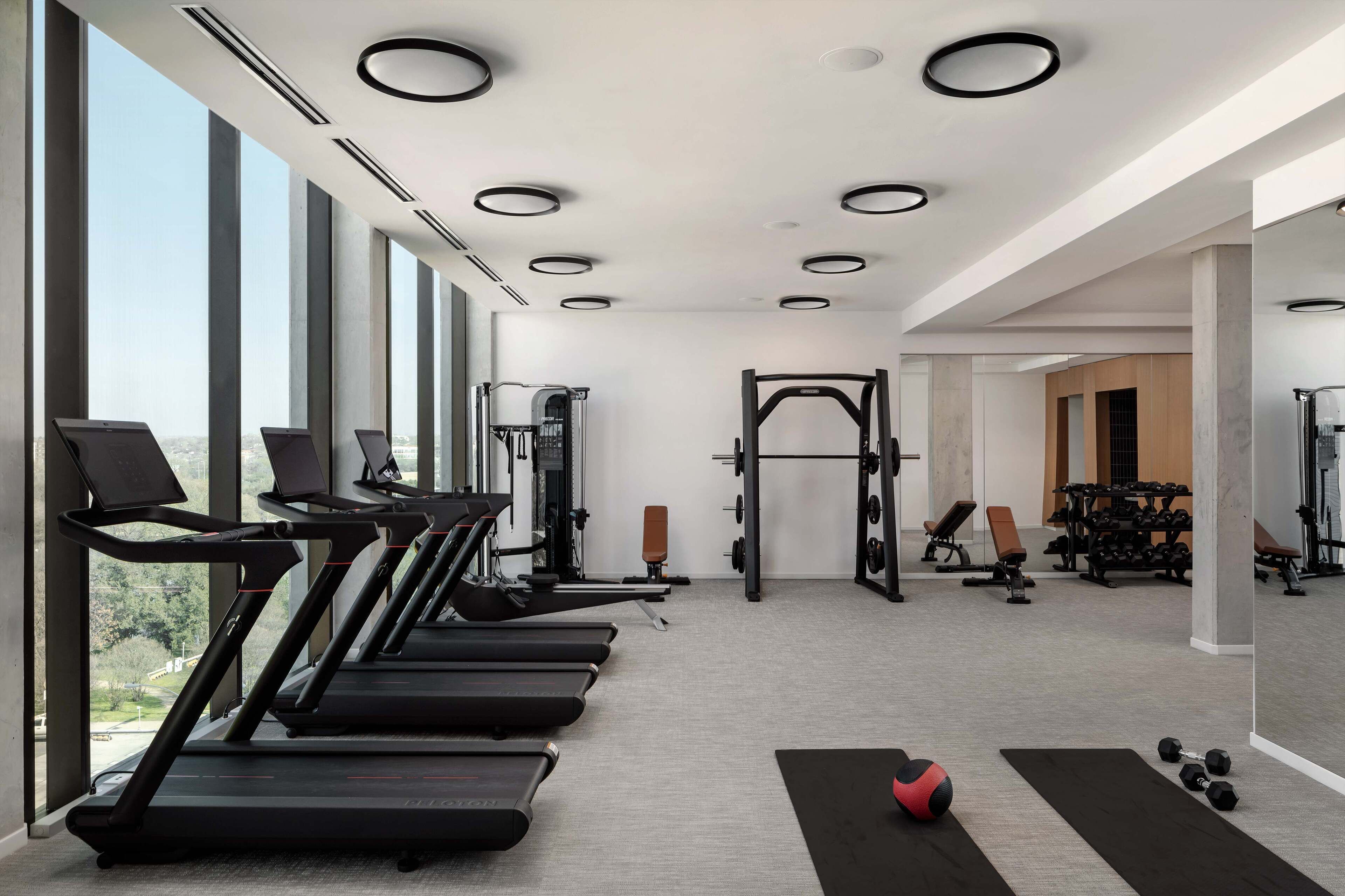 Ein Fitnessstudio mit Laufbändern, Kraftgeräten und Kurzhanteln.