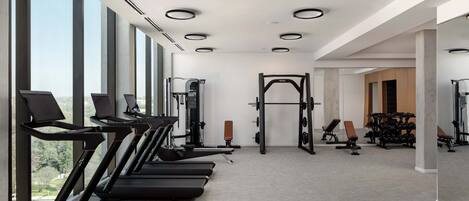 Ein Fitnessstudio mit Laufbändern, Kraftgeräten und Kurzhanteln.