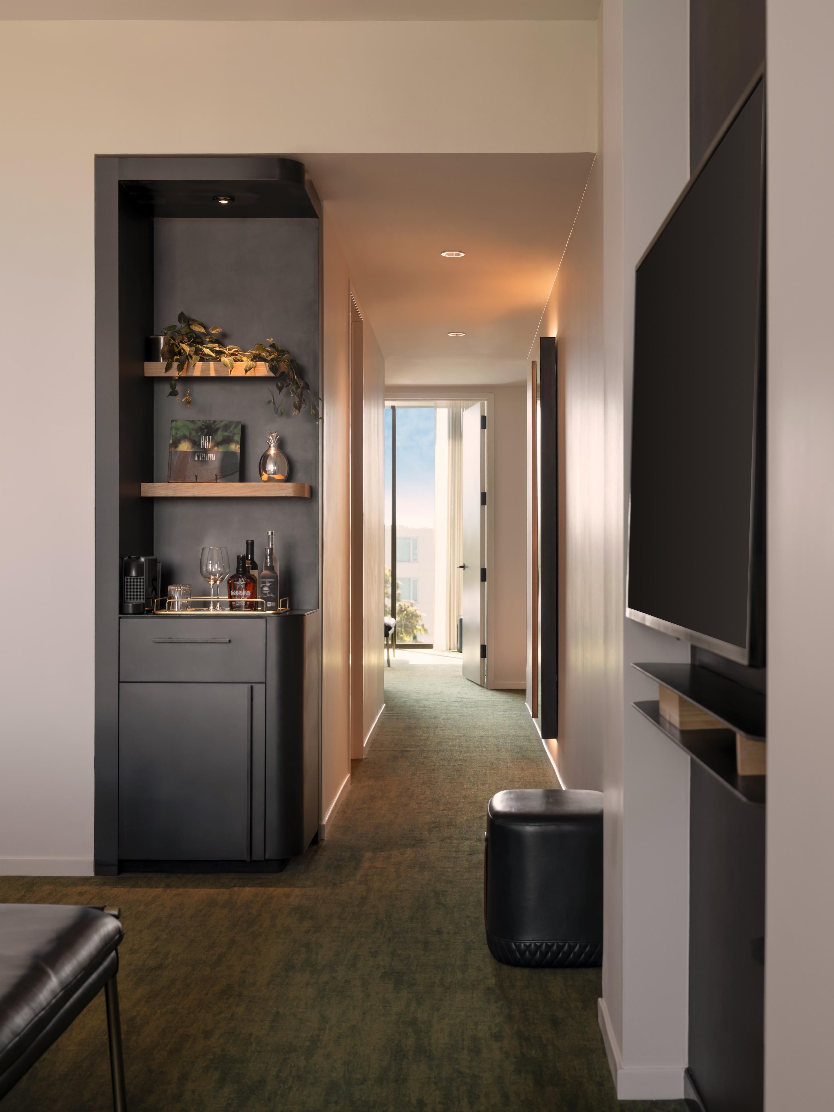 Un pasillo moderno con una zona de cocina, un televisor de pantalla plana y vistas al exterior.