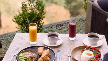 A table with breakfast items, including pancakes, fruit, and coffee, overlooking a scenic view.
