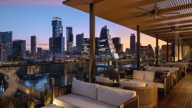 A rooftop lounge with a city view, modern furniture, and a glass railing overlooking a river. - The Loren Hotel Austin, WorldHotels Luxury (Austin)