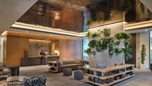 A modern lobby with a reception desk, seating area, and a large planter with greenery. - The Loren Hotel Austin, WorldHotels Luxury (Austin)