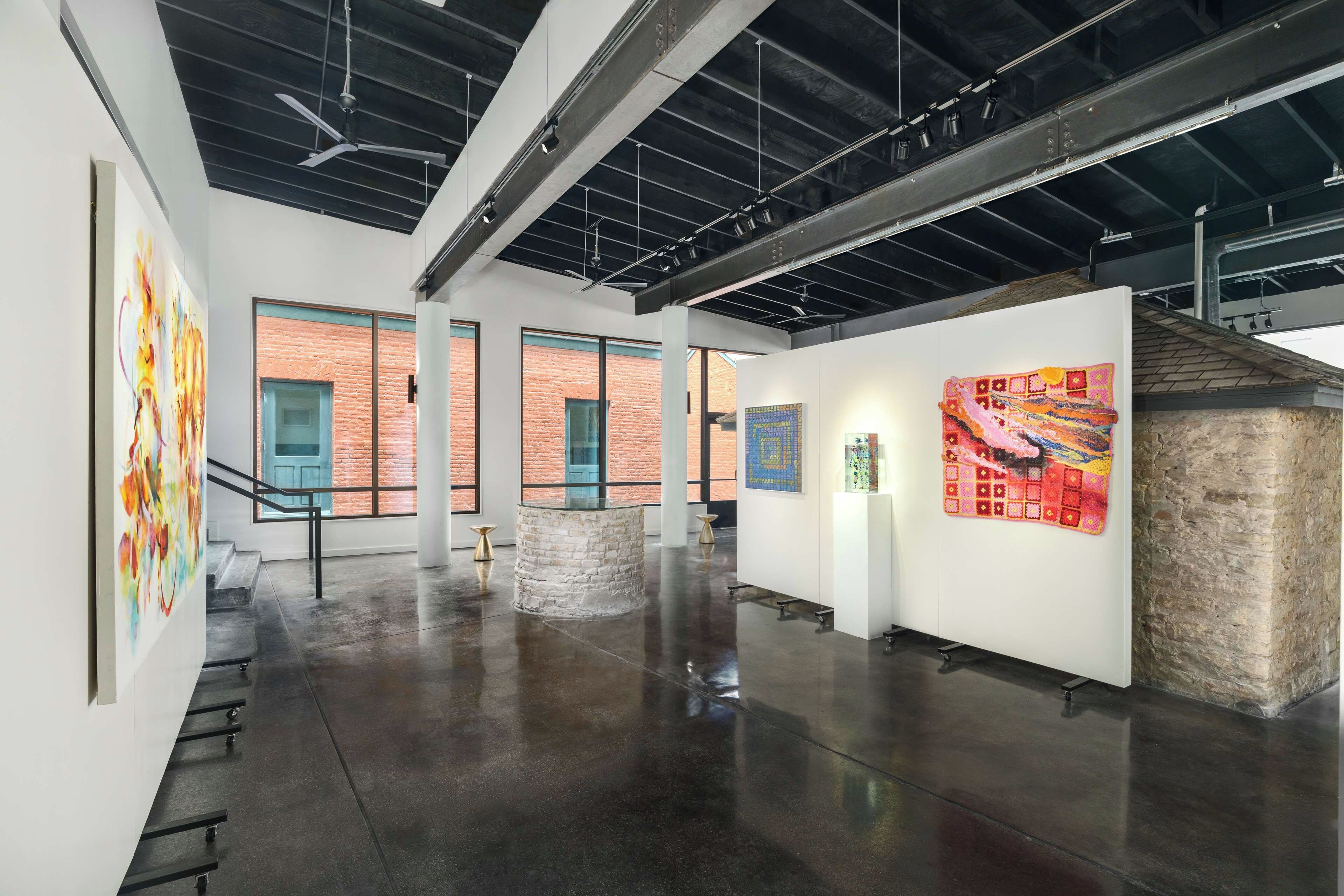 An art gallery with a polished concrete floor, large windows, and a mix of modern and rustic decor.