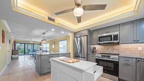 A modern kitchen with grey cabinets, stainless steel appliances, and a central island. - Beachfront Paradise + Complimentary Sanibel Recreation Center Family Pass! (Sanibel Island)
