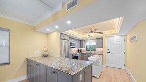 A modern kitchen with granite countertops, stainless steel appliances, and a central island. - Beachfront Paradise + Complimentary Sanibel Recreation Center Family Pass! (Sanibel Island)