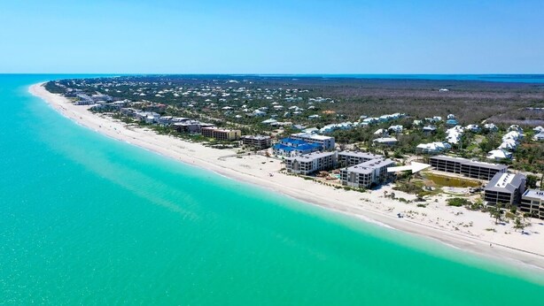 An aerial view of a coastal resort with beachfront properties, a sandy beach, and a clear blue ocean. - Beachfront Paradise + Complimentary Sanibel Recreation Center Family Pass! (Sanibel Island)