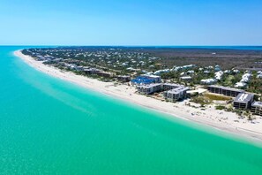 An aerial view of a coastal resort with beachfront properties, a sandy beach, and a clear blue ocean. - Beachfront Paradise + Complimentary Sanibel Recreation Center Family Pass! (Sanibel Island)