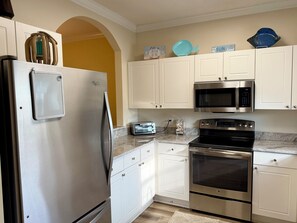 A kitchen with white cabinets, a stainless steel refrigerator, a microwave, an oven, and a toaster.