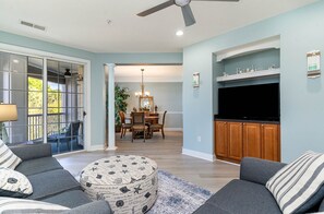Relax in this stylish living room with a large flat-screen TV, comfortable sofa, and round ottoman.