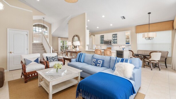 Un vaste espace de vie comprenant un canapé bleu, une table basse blanche et un escalier menant à l’étage supérieur.