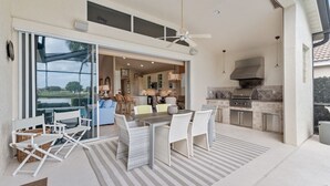 Un espace cuisine extérieur comprenant un coin repas, un ventilateur de plafond et une vue sur l’intérieur.