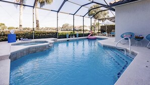 Une piscine avec un jacuzzi, des chaises longues et un espace couvert offrant une vue sur le paysage.
