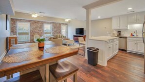 Une cuisine moderne avec des meubles blancs, un îlot central et un coin repas comprenant une table et un banc en bois.