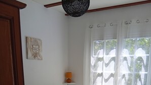 A bedroom with a bed, a wall-mounted lamp, a window with curtains, and a door. - Chalet à la Campagne (Précy-sous-Thil)