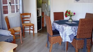 A dining area with a table set for four, surrounded by wicker chairs, a blue and white patterned tablecloth, and a vase with flowers. - Chalet à la Campagne (Précy-sous-Thil)