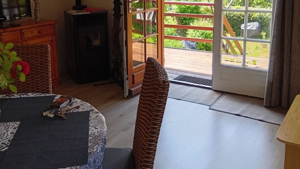 A cozy room with a dining table, chairs, a television, and a view of the outdoors through a glass door. - Chalet à la Campagne (Précy-sous-Thil)