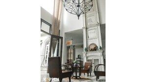 Une pièce spacieuse agrémentée d’un lustre, d’une cheminée et d’un coin repas avec des chaises et une table.