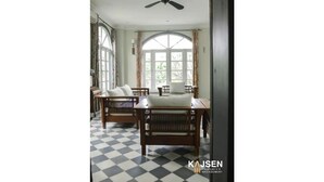 Une pièce avec un sol à carreaux, deux chaises en bois, une table et un ventilateur de plafond.