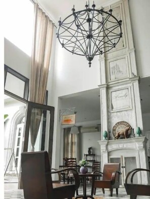 Une pièce spacieuse agrémentée d’un lustre, d’une cheminée et d’un coin repas avec des chaises et une table.