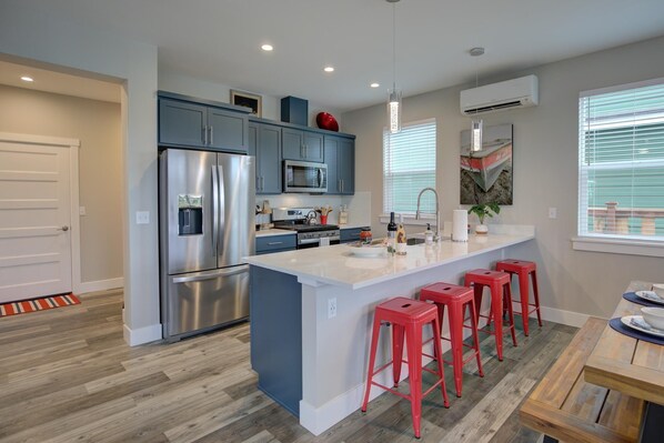 A modern kitchen with a central island, stainless steel appliances, and red bar stools.