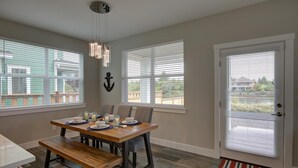 A dining area with a wooden table set for four, a bench, and a chandelier.