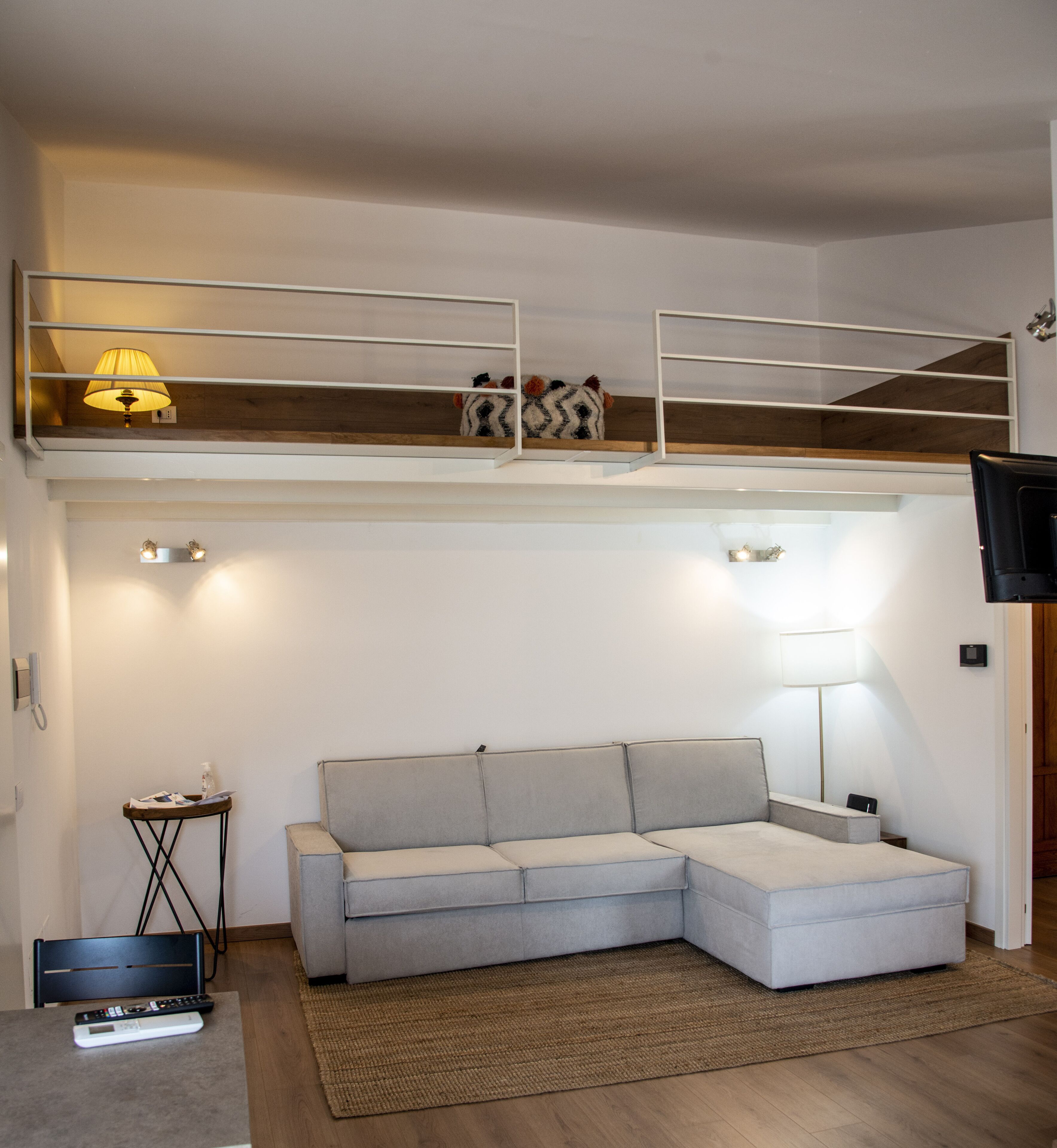 A modern living room with a sofa, a small side table, and a TV.