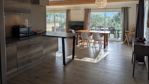 A modern kitchen with a central island, wooden flooring, and a dining area with a table and chairs.