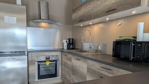 A modern kitchen with a stainless steel refrigerator, built-in oven, and a microwave.