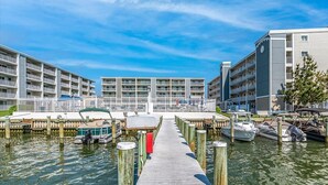 A marina with docked boats, a wooden pier, and multi-story buildings with balconies. - Thunder Island Condo - Beautiful 2 BR 2 BA Next to Convention Center (Ocean City)