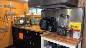 Una cucina con un piano di lavoro in legno, una macchina per il caffè, un frullatore e una scatola di Cheerios.